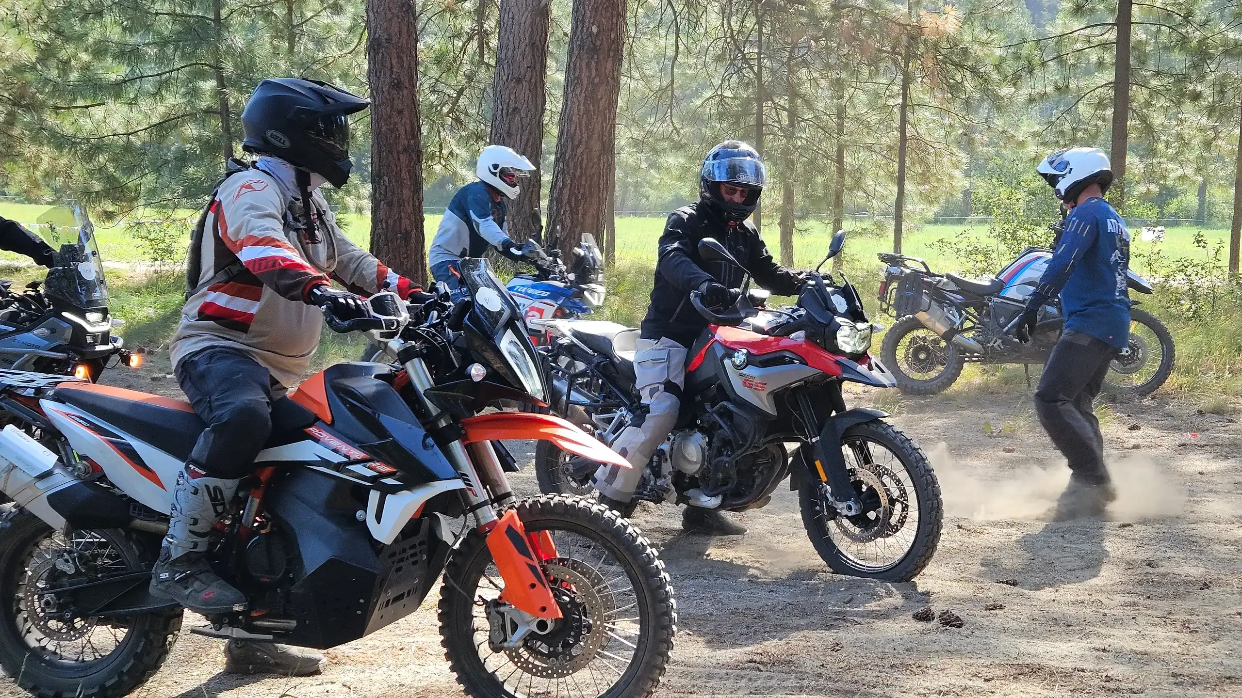 Riders on adventure bikes practice braking in a dusty pine-forest clearing, Washington