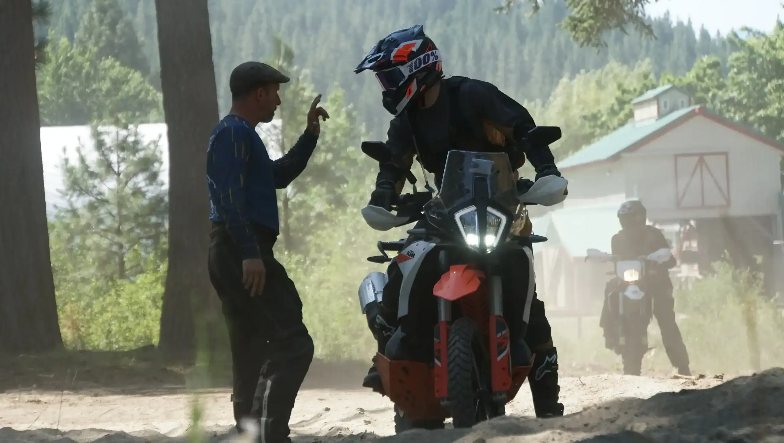 Bret Tkacs signals a rider on an orange adventure bike during a braking drill, a barn behind, Washington