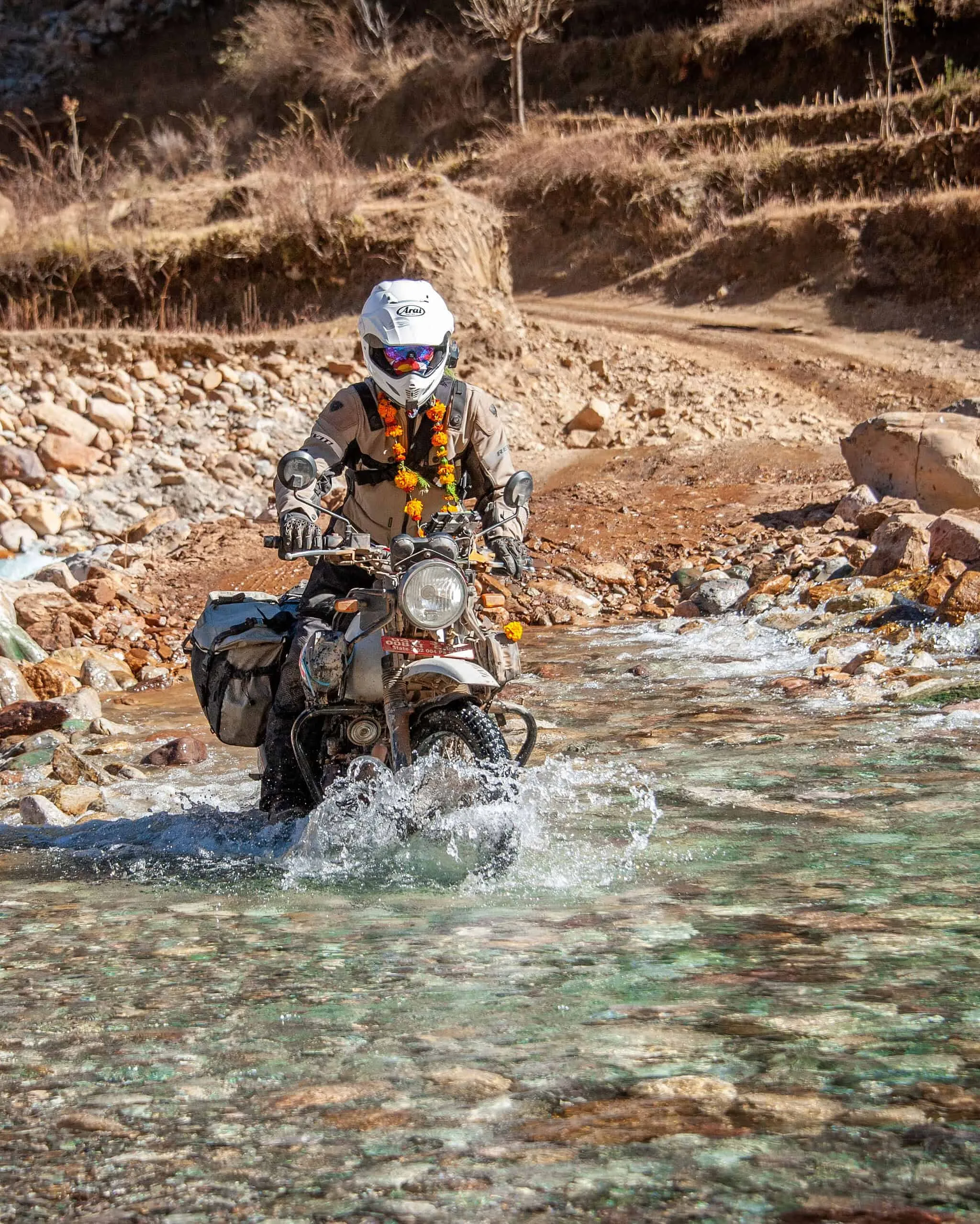Bret Tkacs rides a Royal Enfield Himalayan through a shallow river crossing, Nepal