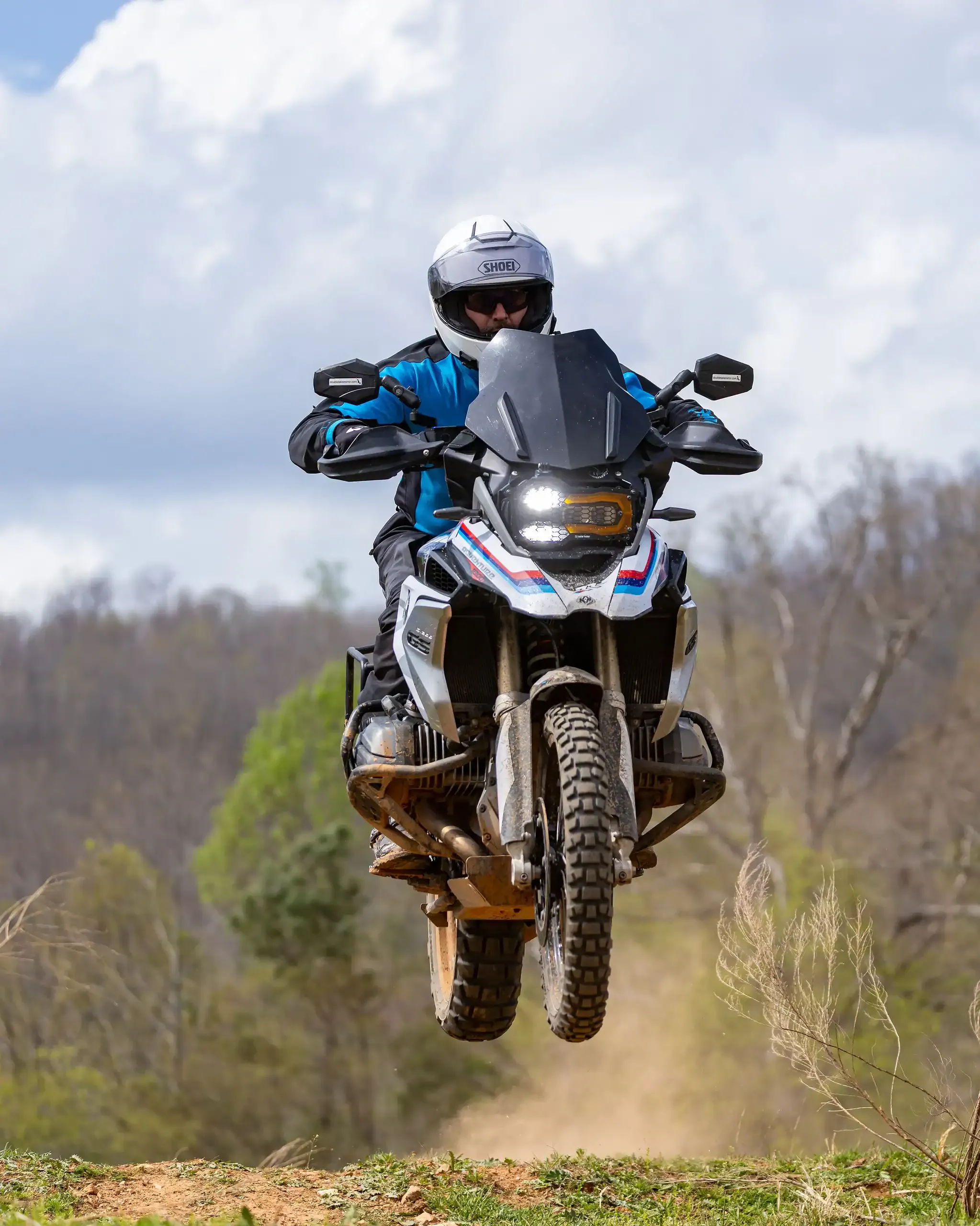 Bret Tkacs launches a BMW adventure bike off a rise, both wheels in the air